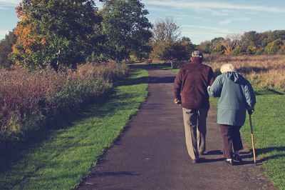 Older lady and gentleman walking on a path with walking aid